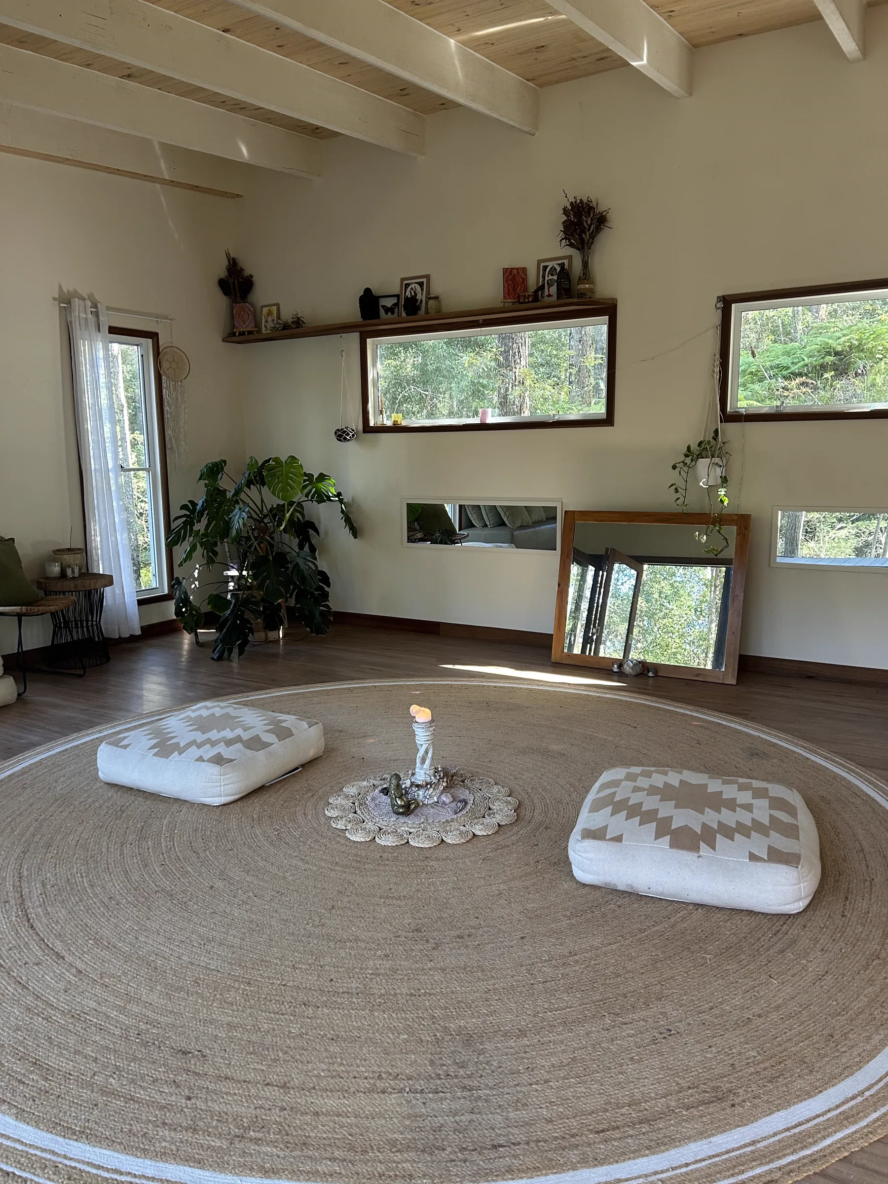 The temple room at Ilkley Haven with floor cushions on a round jute rug, altar candle and forest light through the windows